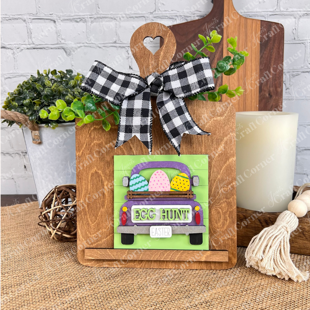 Hello Easter Squares from Janet's Craft Corner feature a wooden stand with a heart cutout, holding a sign with a green truck, colorful Easter eggs, "EGG HUNT!", "EASTER," plaid bow, and greenery—perfect festive decor!.