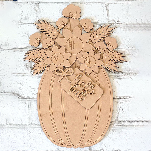 Introducing the Fall Floral Pumpkin Door Hanger by Janet's Craft Corner: a charming, hand-painted rustic wooden accent in the shape of a pumpkin, adorned with delightful flowers and leaves on top. A quaint small sign reading "hello fall" is affixed to the front, perfect for enhancing your personalized home decor against the backdrop of a white brick wall.