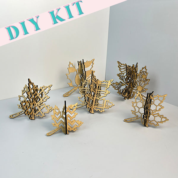 The Fall Leaves Set of Six 3-D Shelf Sitters by Janet's Craft Corner features intricate wooden puzzle pieces shaped like various trees and leaves. Ideal for rustic décor, these cut-out designs are displayed on a light gray background, bringing a charming touch to any home setting.