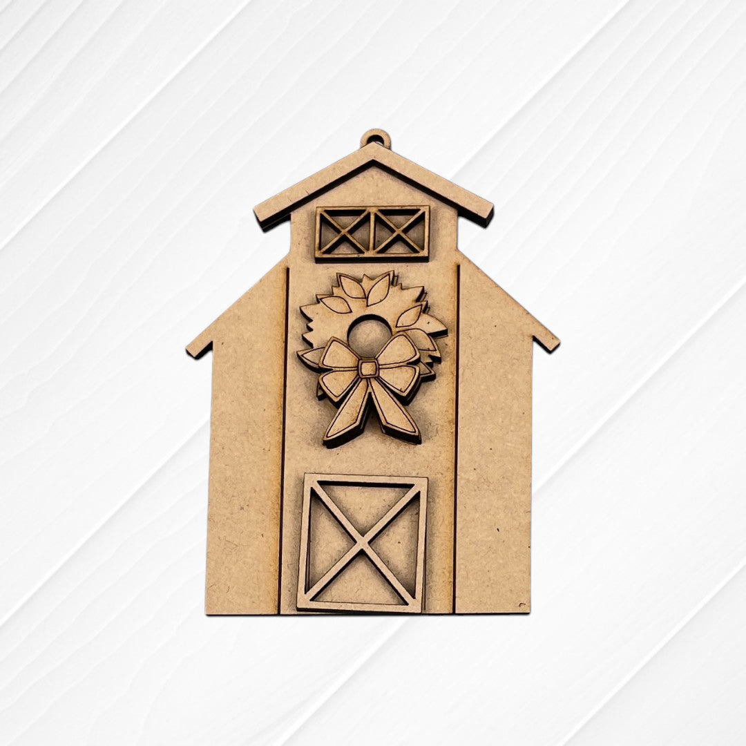 The Farm Life Christmas Ornaments DIY kit by Janet's Craft Corner features a barn-shaped design with a wreath, bow, and X-pattern door on a white textured background. Choose from 4 seasonal ornament styles to craft yourself!.
