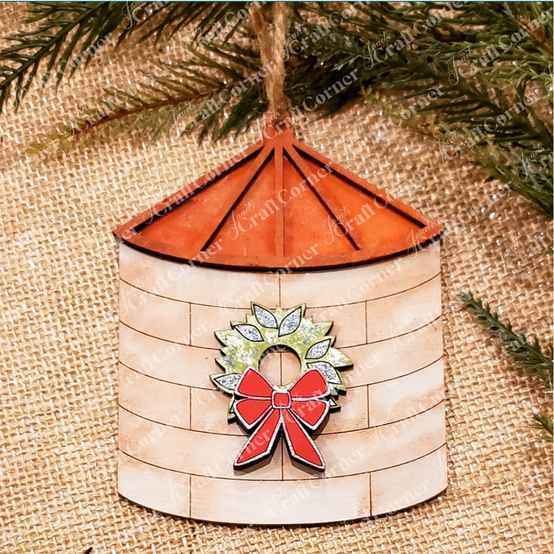 The Farm Life Christmas Ornaments DIY craft kit by Janet's Craft Corner features a silo-shaped ornament with a red roof, beige sides, and green wreath—ideal for farm-themed collections or festive crafting. Choice of 4 designs available.