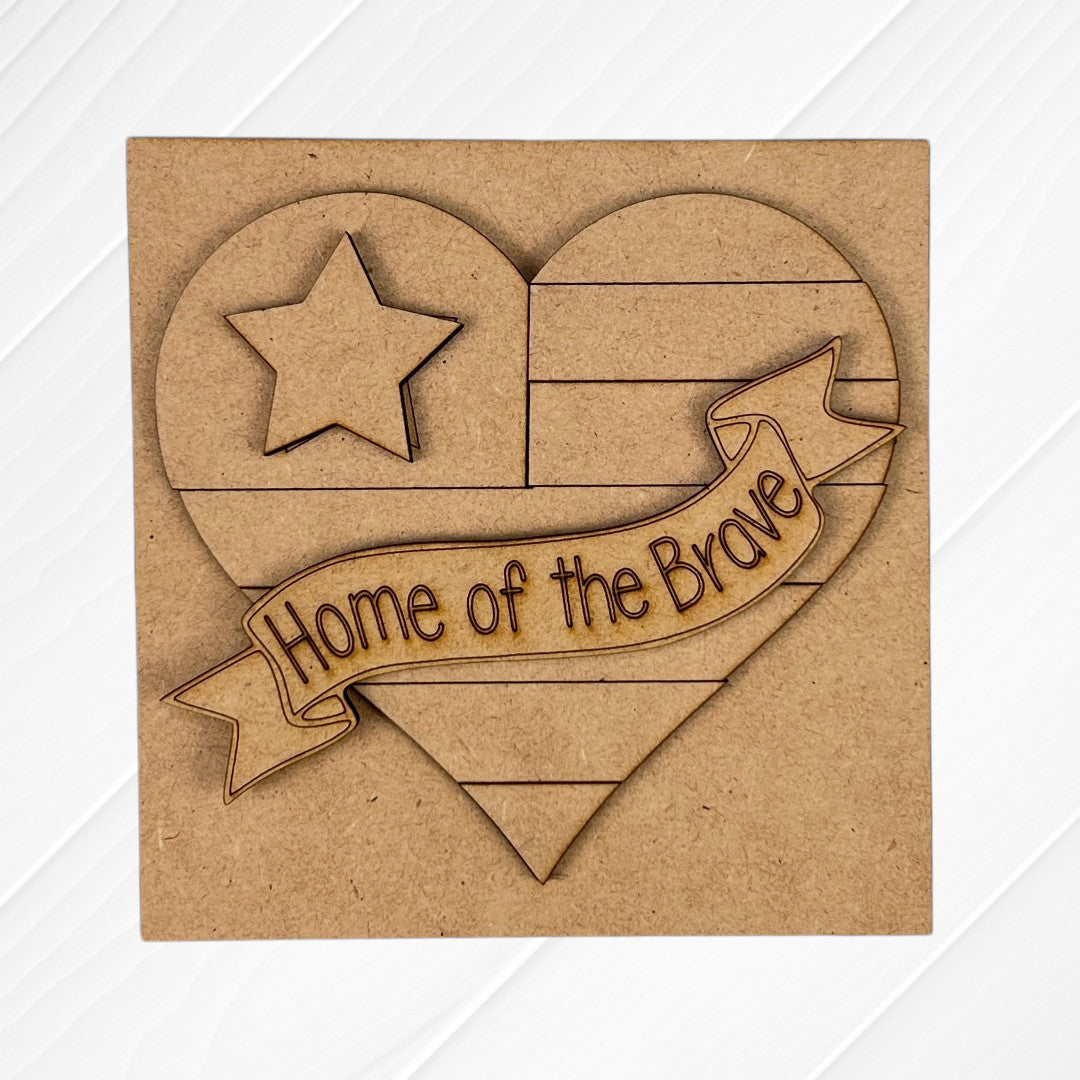 Janet's Craft Corner presents "Military Squares": a white wooden plaque featuring an engraved heart with stripes, a star, and a raised "Home of the Brave" banner—ideal for tiered tray decor.
