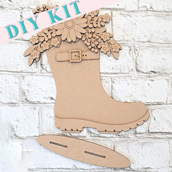 Introducing the Floral Rainboot Shelf Sitter from Janet's Craft Corner: a delightful wooden craft shaped like a boot decorated with flowers, ideal for home décor. This DIY kit comes ready for assembly and includes a base piece with slots, set against a white brick wall backdrop.