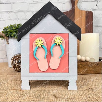 The Summer Lovin Swappable Squares DIY seasonal home decor craft kit by Janet's Craft Corner features a wooden house-shaped sign with a black roof and pink flip-flops—perfect as charming tiered tray decor among your favorite home accents.