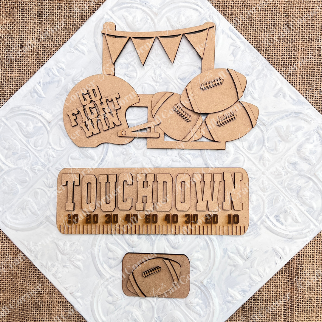 Transform your space with Janet's Craft Corner's Football Interchangeable Insert DIY home decor kit. This hand-painted set features wooden cutouts, including a football helmet inscribed with "Go Fight Win," four footballs, and a “Touchdown” sign above a yard line. It also comes with an additional smaller football insert at the bottom – perfect for adding a personalized touch to your decor.