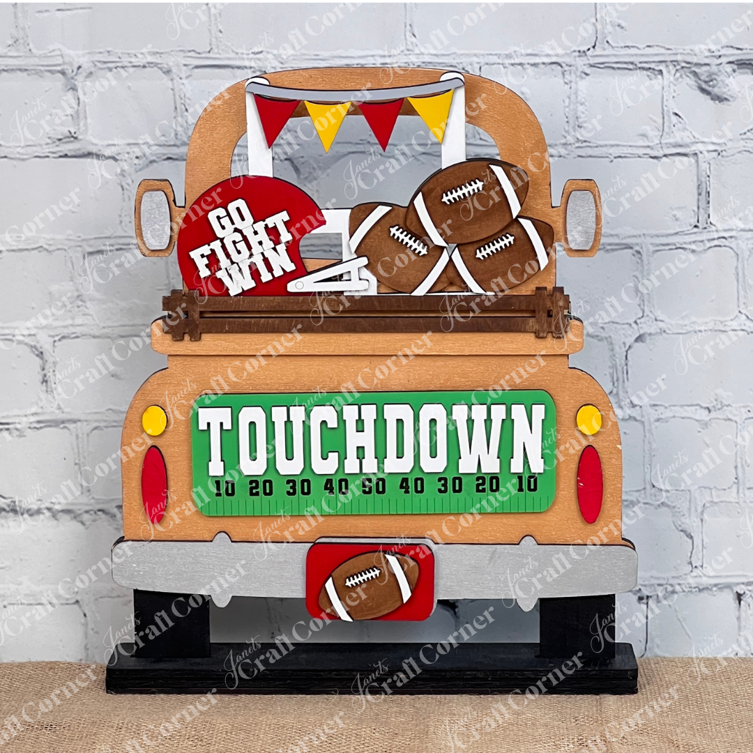 Introducing the Football Interchangeable Insert DIY home decor kit by Janet's Craft Corner: This charming copper  truck set showcases football-themed red & gold accents, including interchangeable footballs, helmets with "Go Fight Win," a goalpost, and a "Touchdown" sign. Perfectly set against a white brick wall backdrop, it offers an ideal project for hand-painted DIY craft enthusiasts looking to add a personal touch to their decor.
