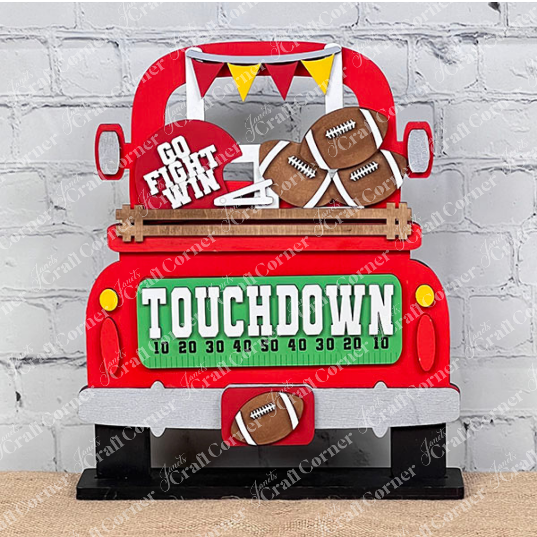 Introducing the Football Interchangeable Insert DIY home decor kit by Janet's Craft Corner: This charming red truck set showcases football-themed accents, including interchangeable footballs, helmets with "Go Fight Win," a goalpost, and a "Touchdown" sign. Perfectly set against a white brick wall backdrop, it offers an ideal project for hand-painted DIY craft enthusiasts looking to add a personal touch to their decor.