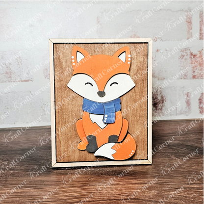 The "Fall in the Forest Switchable Farmhouse Signs" DIY kit by Janet's Craft Corner features a cartoon orange fox with a blue scarf on light brown wood—perfect for woodland or fall farmhouse decor. Displayed upright on a gray surface.
