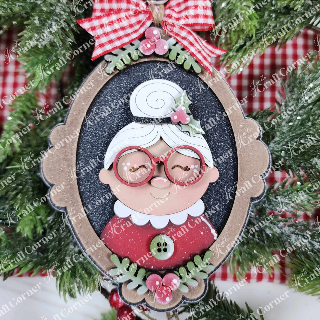 Add charm to your Santa Ornaments collection with Janet's Craft Corner Mrs. Claus Ornaments—a vintage frame-shaped festive ornament featuring a smiling grandmother with white hair, red glasses, and a gingham bow for your tree.