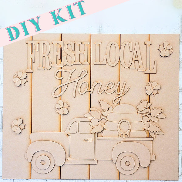 This charming DIY kit from Janet's Craft Corner, the "Fresh Local Honey Shelf Leaner," features a vintage truck hauling a beehive, beautifully framed by honeycomb patterns, making it an ideal piece for rustic home décor.