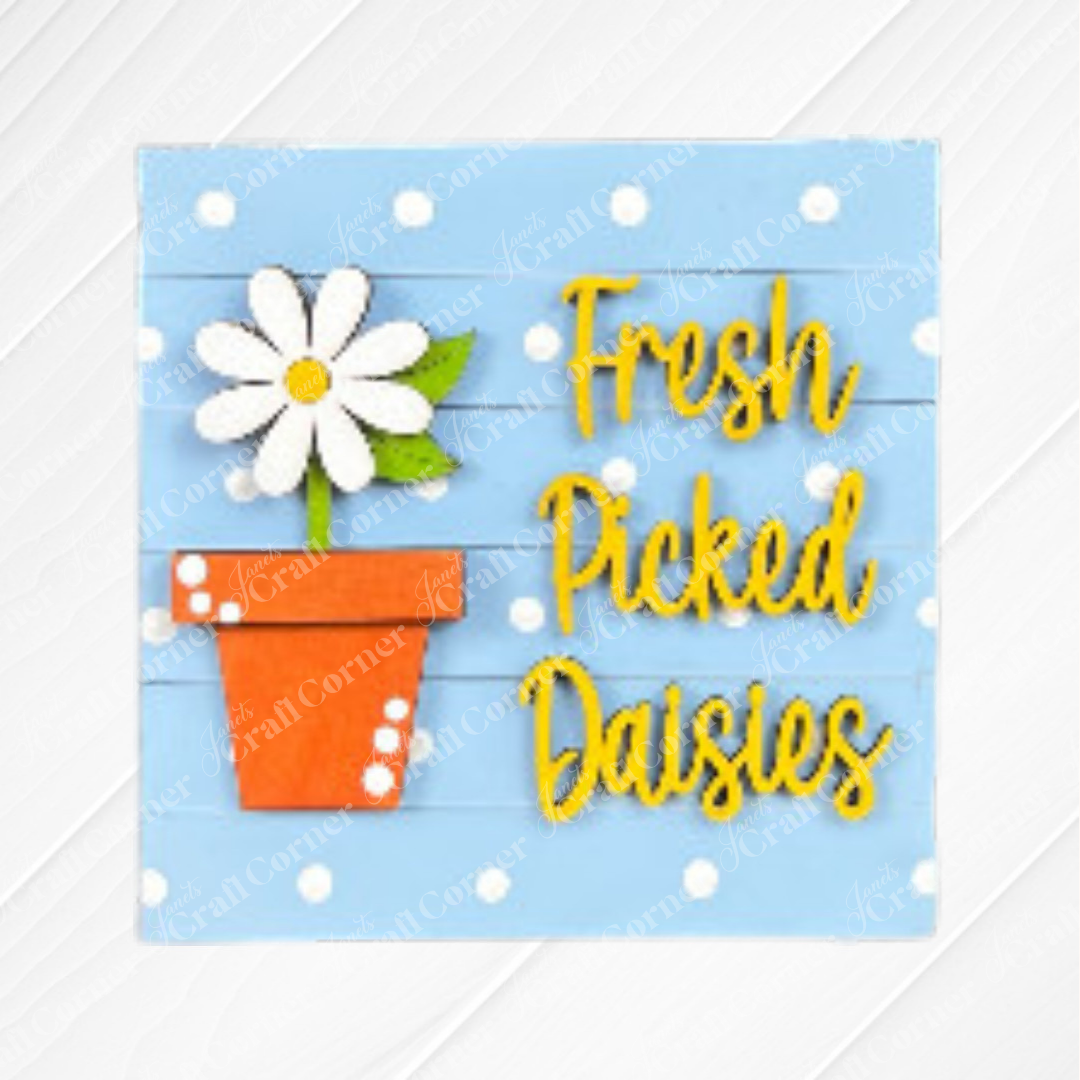 A graphic of a white daisy in an orange pot on a blue polka-dot background with "Fresh Picked Daisies" in yellow. Great for tiered tray decor or as part of Janet's Craft Corner Bloom & Grow Squares wood sign kit.