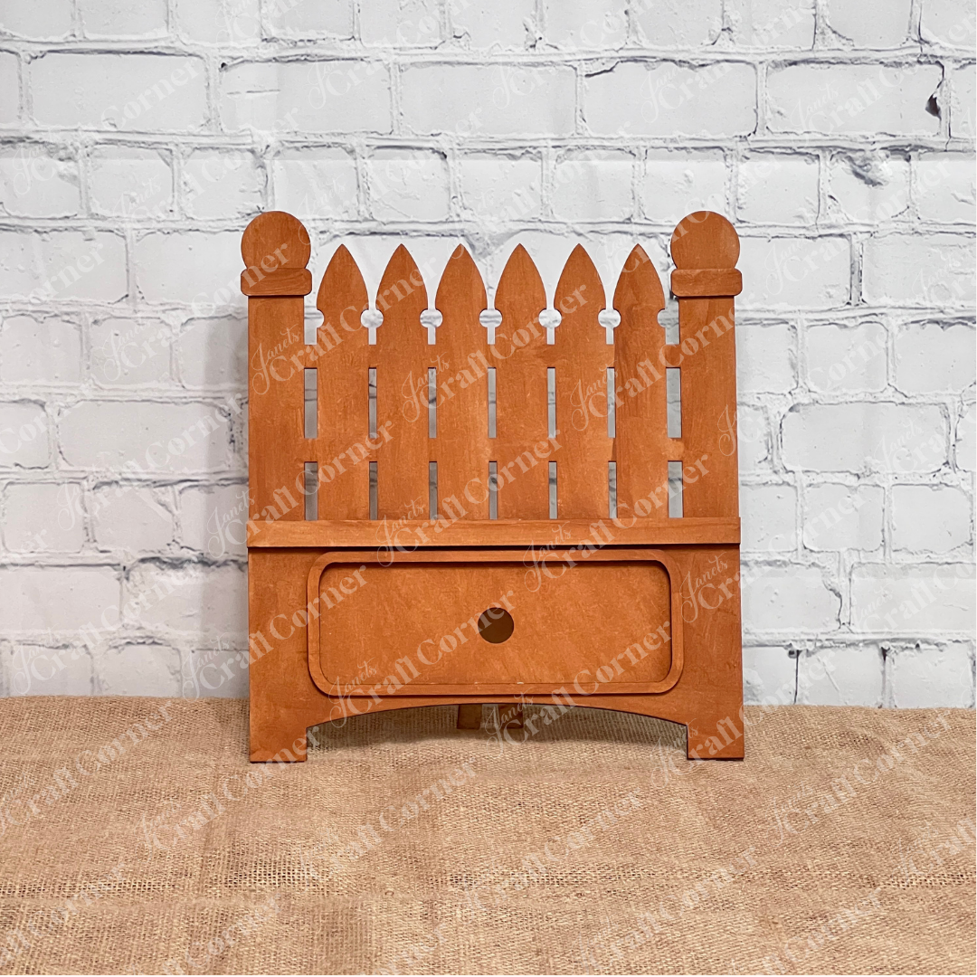 Janet's Craft Corner Garden Fence Interchangeable Base DIY home decor kit  shown stained in front of a white brick wall.