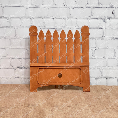 Janet's Craft Corner Garden Fence Interchangeable Base DIY home decor kit  shown stained in front of a white brick wall.