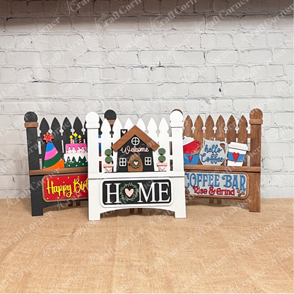 Janet's Craft Corner offers a Picket Fence DIY kit, perfect for home décor. Each set shows a fence base with a themed insert like "Welcome Home," "Happy Birthday," or "Coffee Bar." Hand-painted, they add charm to your space against any brick wall backdrop.