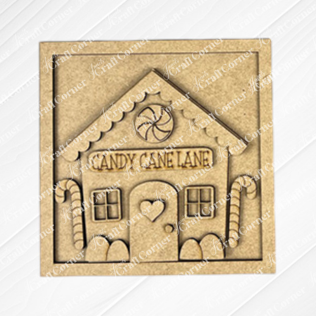 The Gingerbread Squares plaque by Janet's Craft Corner is perfect for tiered trays, featuring a gingerbread house with "Candy Cane Lane" above the door, candy cane accents, a heart on the door, and a peppermint candy above the roof.