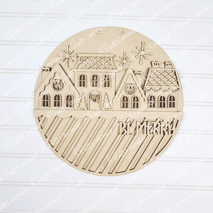 Janet's Craft Corner Gingerbread Village Door Hanger features engraved snowy houses, snowflakes, stars, and diagonal stripes with "BE MERRY!"—a festive décor or DIY craft kit to brighten your holidays.