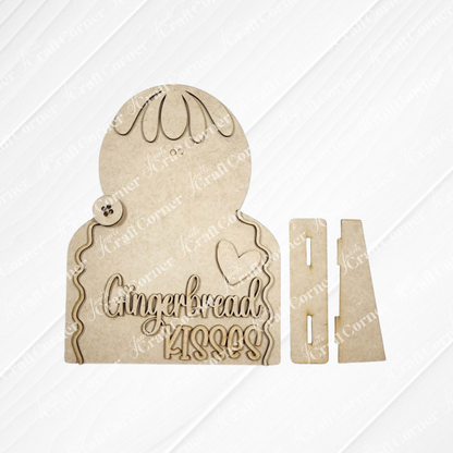 Create your own festive decor with Janet’s Craft Corner’s Gingerbread Kisses Shelf Sitter - DIY home decor craft kit (set of 1). This unpainted wooden cutout set includes pieces for assembling a delightful “Gingerbread Kisses” sign, complete with a gingerbread figure outline, heart, button, and separate stand pieces—all displayed on a white textured background. This craft kit is perfect for adding a charming holiday touch to your home.