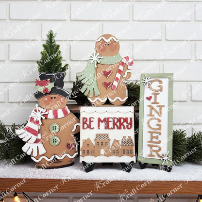 Janet's Craft Corner’s Gingerbread Mini Shelf Sitters DIY kit includes a snowman, gingerbread person with mint, and “GINGER” sign to create charming seasonal home decor amid greenery and “BE MERRY” blocks against a white brick wall.