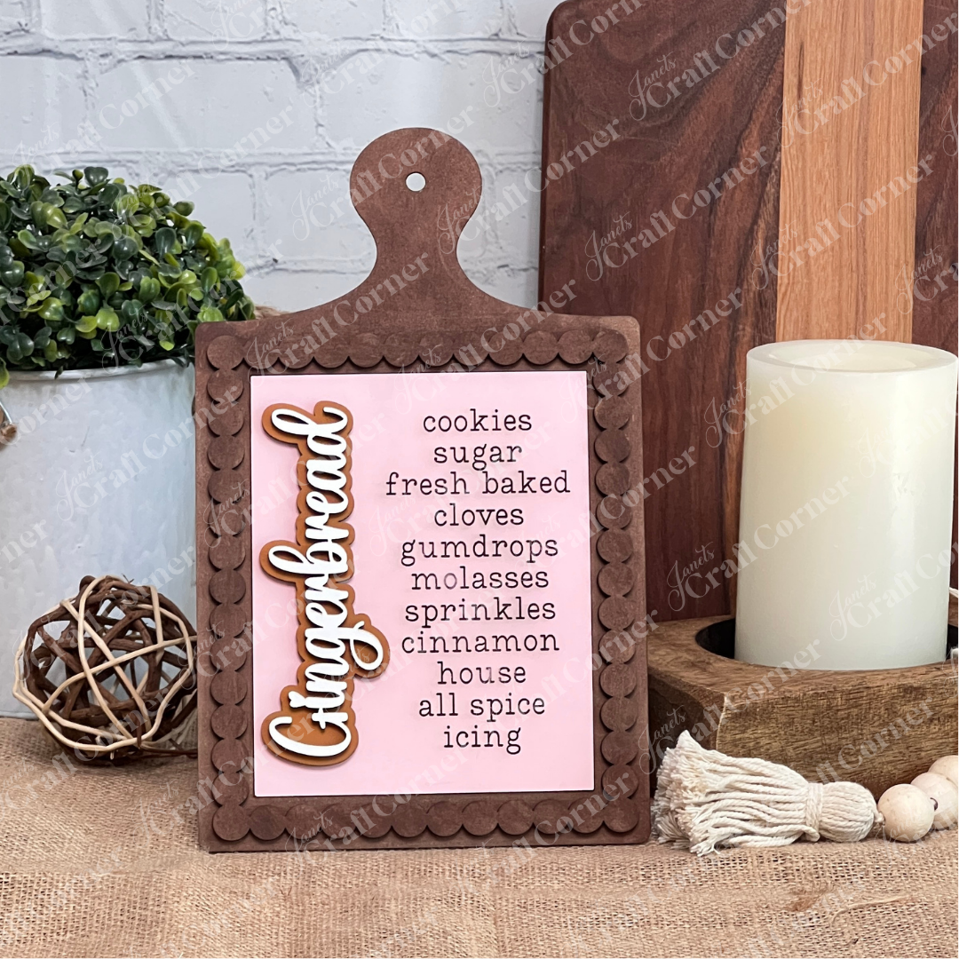 Janet's Craft Corner Bead Trim Breadboard Frame, a DIY farmhouse decor kit for switchable signs, is styled on a table with a candle, plant, and tassel for seasonal charm.