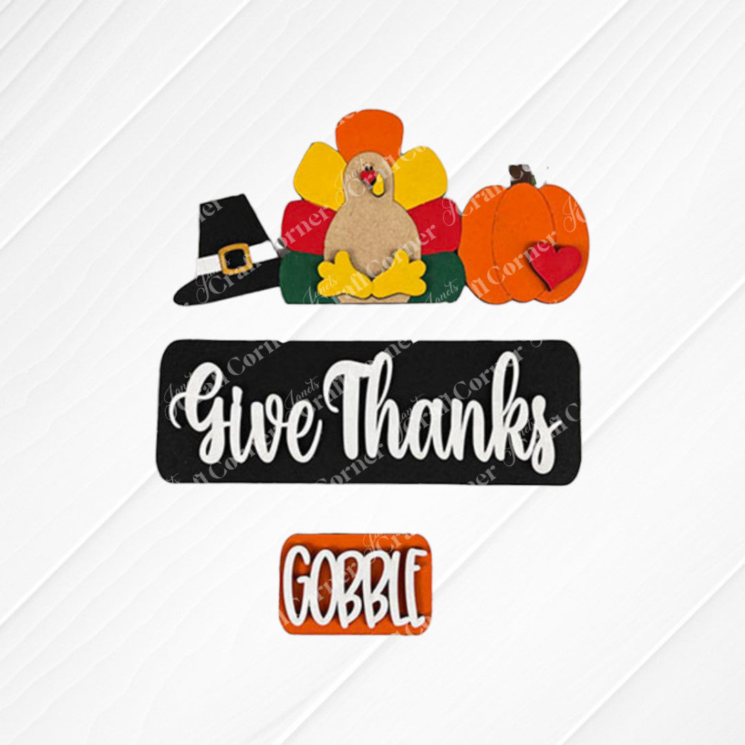 Enhance your home for Thanksgiving with Janet's Craft Corner's Give Thanks Interchangeable Insert - Painted, featuring a textured surface adorned with hand-painted ornaments such as a turkey, a pilgrim hat, and a pumpkin with a heart. Finish off your festive decor with two delightful signs that say "Give Thanks" and "Gobble," perfect for interchangeable craft displays!