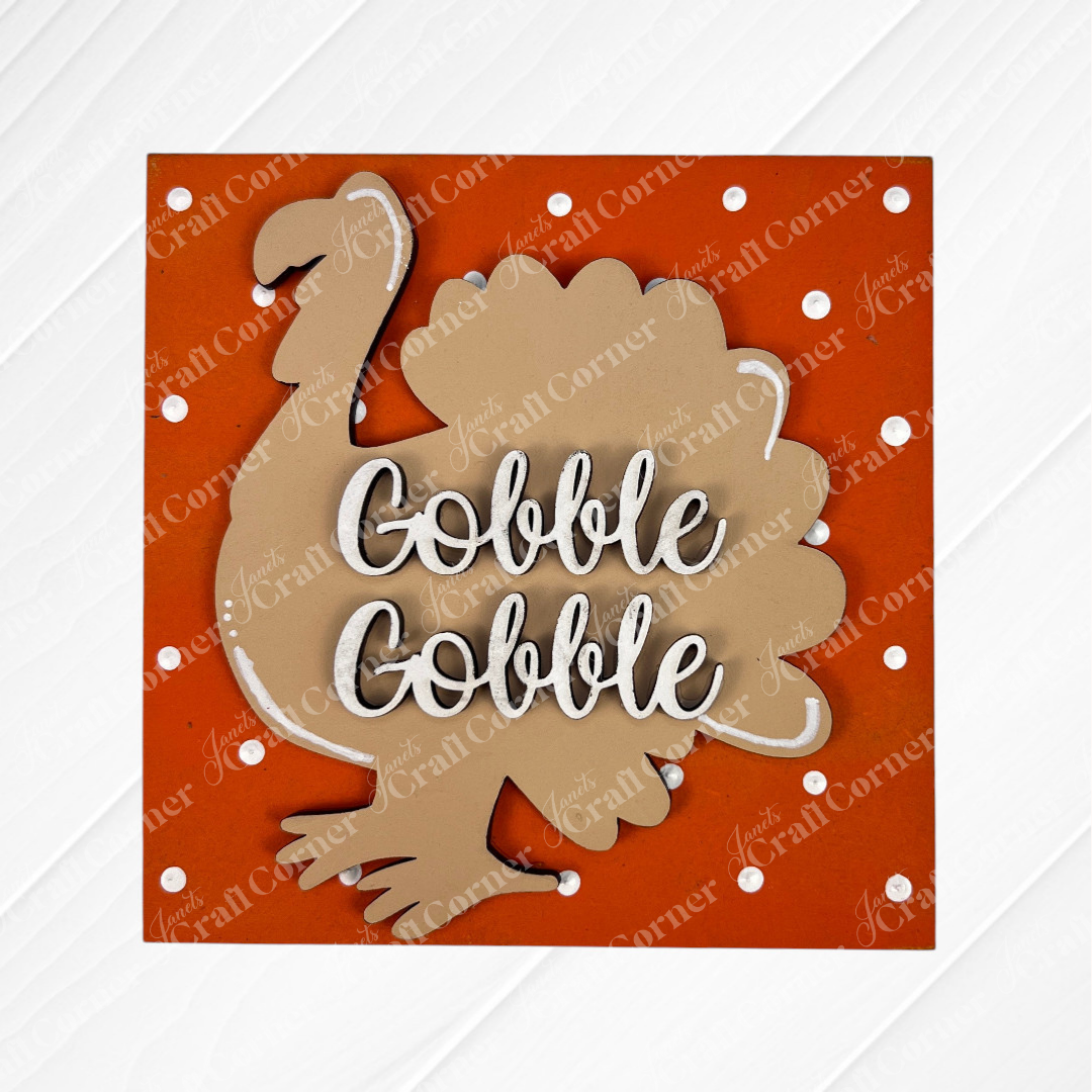 A brown turkey silhouette on an orange, polka-dotted background with “Gobble Gobble” in white—part of the Thanksgiving Feast Squares collection by Janet's Craft Corner. Great for tiered tray decor or adding to your Swappable Squares cut-outs.