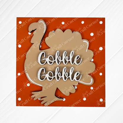 A brown turkey silhouette on an orange, polka-dotted background with “Gobble Gobble” in white—part of the Thanksgiving Feast Squares collection by Janet's Craft Corner. Great for tiered tray decor or adding to your Swappable Squares cut-outs.