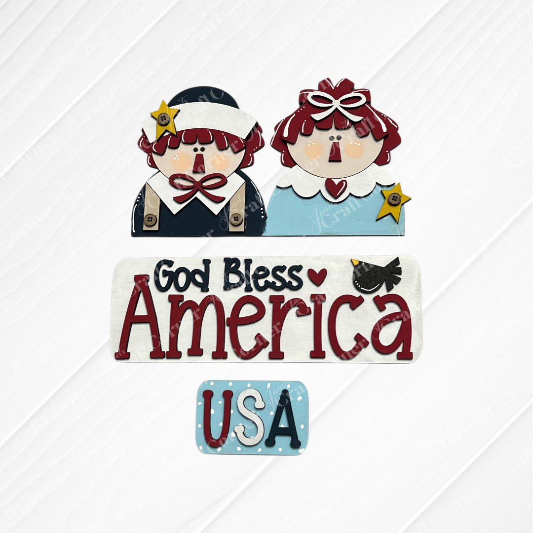 The God Bless America Interchangeable Insert DIY craft kit by Janet's Craft Corner features two patriotic cartoon figures, a "God Bless America" sign with a bird, and a "USA" blue dot sign—perfect for seasonal decor projects. Set includes 3 pieces.