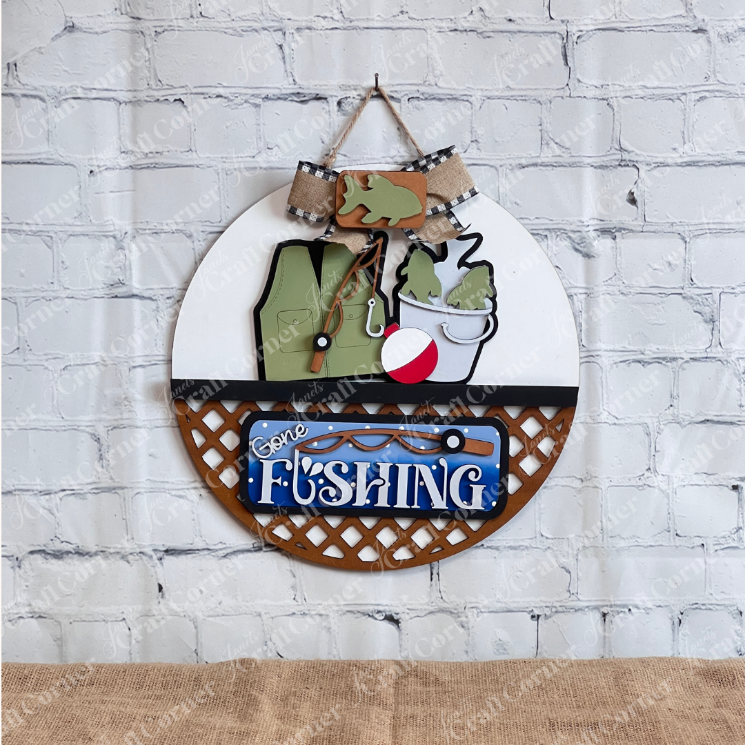 The Gone Fishing Interchangeable Insert by Janet’s Craft Corner is a DIY seasonal home decor craft kit (set of 3) featuring a fishing vest, fish, bucket, bobber, and "Gone Fishing" sign—perfect for your next crafting adventure.