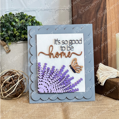 Janet's Craft Corner’s Lavender Switchable Farmhouse Signs DIY Craft Kit includes a handmade card with a wooden “home” script, butterfly, and lavender on scalloped grey—ideal as tiered tray décor or a farmhouse sign. Decor and plants in the background.