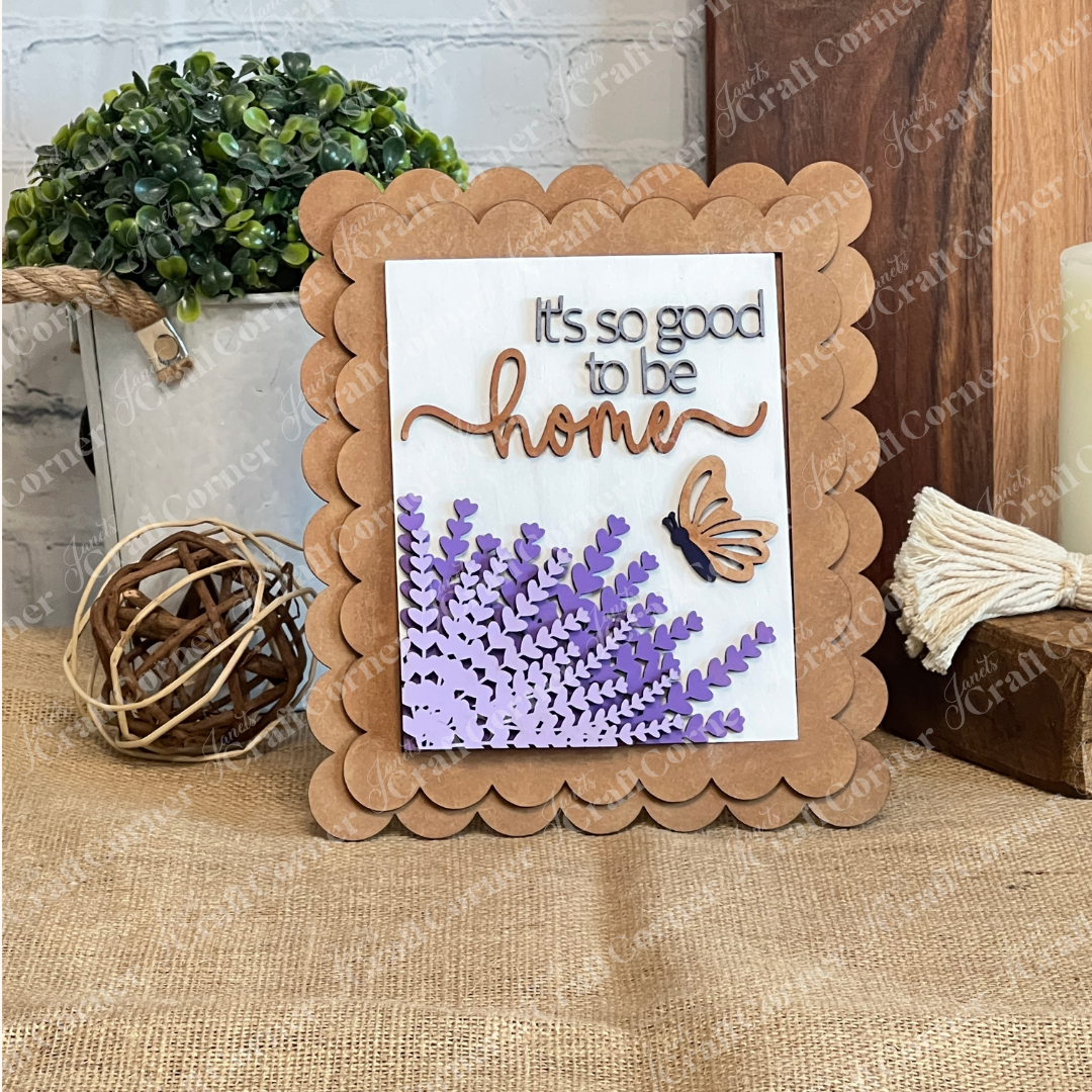 Janet's Craft Corner’s Lavender Switchable Farmhouse Signs DIY Craft Kit features a scalloped-edge sign with "It's so good to be home," flowers, and butterfly—perfect rustic tiered tray décor for your farmhouse table.