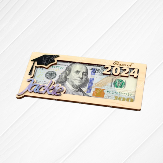 The Graduation Money Holder by Janet's Craft Corner showcases a $100 bill with “Class of 2024,” a graduation cap, and “Jackie” in script on a gold-bordered frame—an ideal personalized gift for graduates.