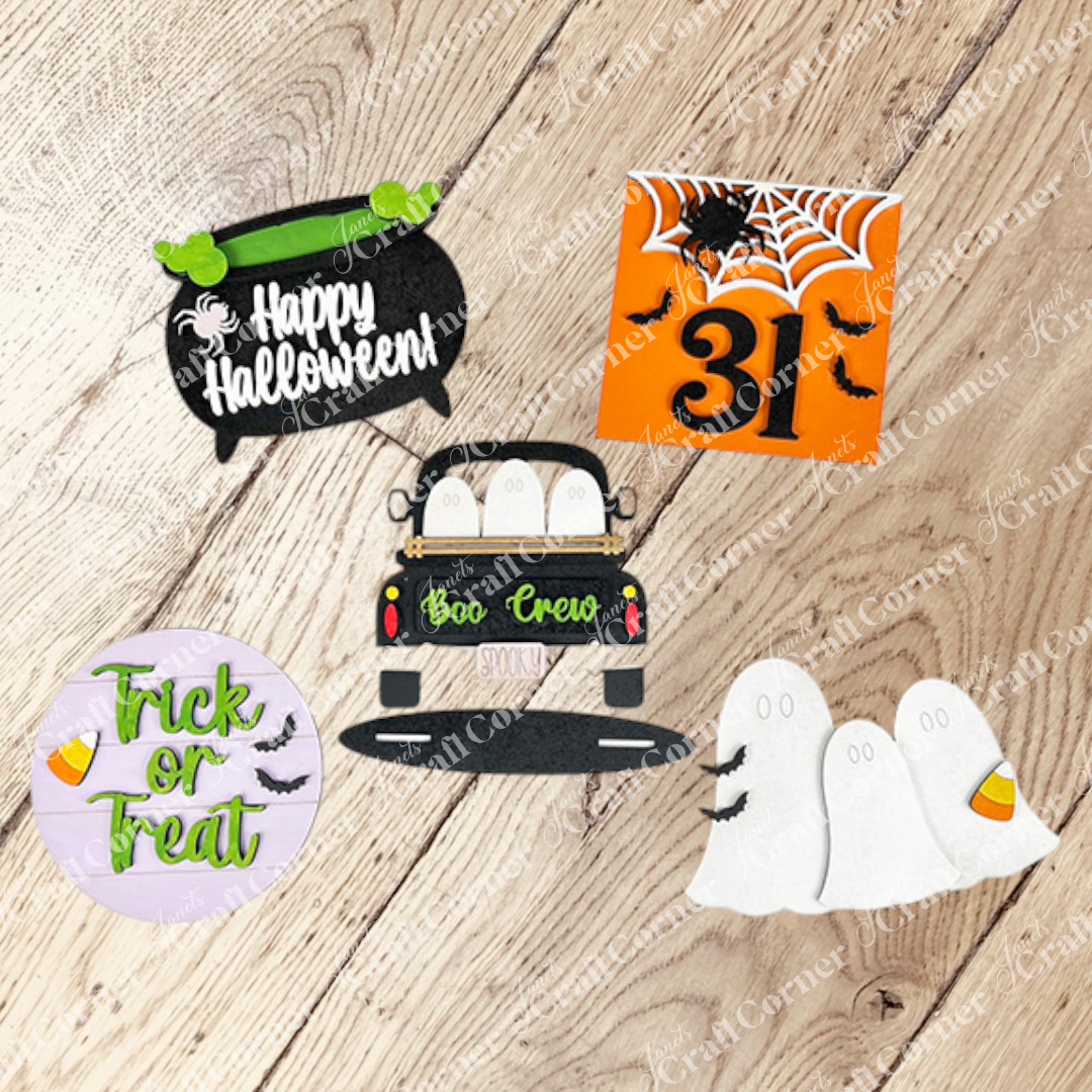 Janet’s Craft Corner Halloween Mini Shelf Sitters DIY kit includes five colorful wooden pieces—cauldron with “Happy Halloween,” orange “31” square, “Trick or Treat,” ghosts in a car, and three ghost figures—for festive seasonal décor.