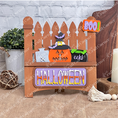 The Garden Fence with Insert from Janet's Craft Corner is a charming wooden Halloween decor featuring a picket fence design. It includes interchangeable elements like a pumpkin in a witch hat, "POISON" sign, green "eek!" cauldron, and colorful "BOO!" and "HALLOWEEN" signs, perfect for DIY lovers.
