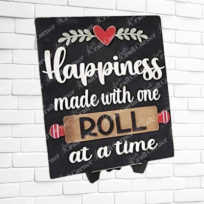 Janet's Craft Corner Kitchen Switchable Farmhouse Sign displays "Happiness made with one roll at a time," with "ROLL" on wood and a red heart, adding charming rustic decor to your kitchen. DIY home decor craft kit - Set of 1.