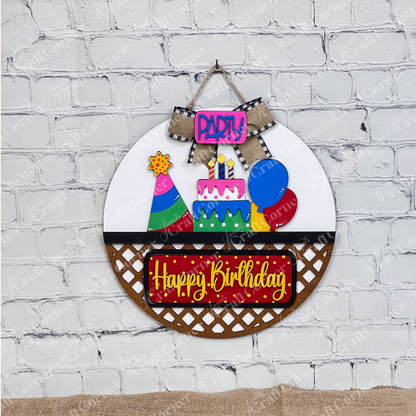 Janet's Craft Corner offers a festive Birthday Interchangeable Insert DIY home decor kit. It features a round base with a cake, balloons, and party hat. The words "Party" in purple and "Happy Birthday" in yellow on red are highlighted with a black and white checkered bow.