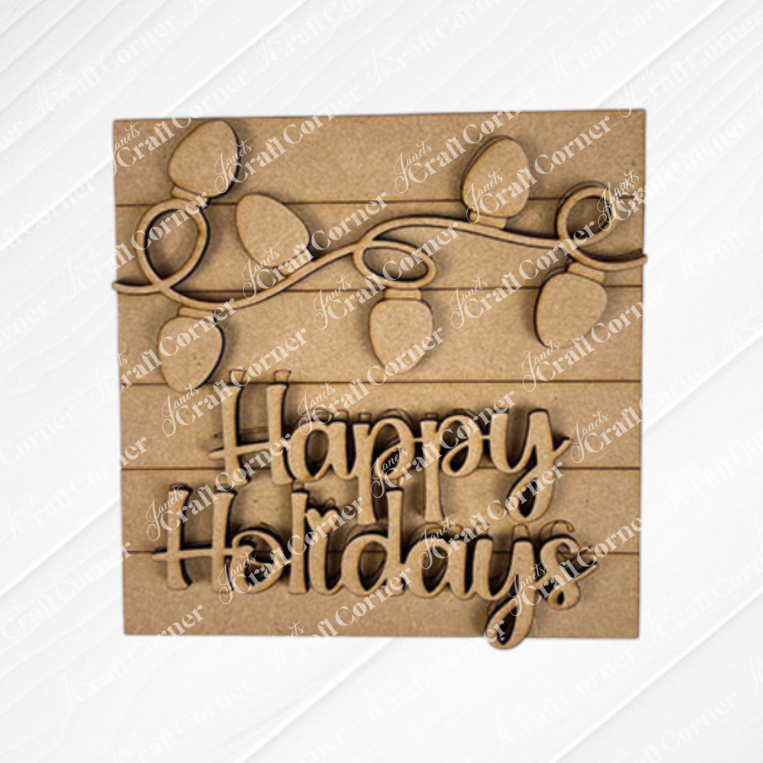 The Christmas Icon Swappable Squares DIY craft kit by Janet's Craft Corner features a rustic wooden sign with string lights and "Happy Holidays" in cursive—perfect for seasonal decor or swapping with other square signs year-round.