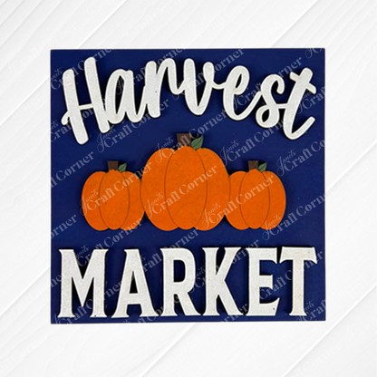 The "Hello Fall Squares" sign by Janet's Craft Corner features bold white letters on dark blue, three orange pumpkins, and is ideal for tiered tray decor or paired with wood cut-outs for a festive autumn accent.