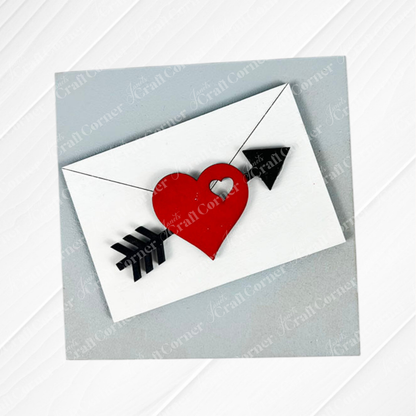 Janet's Craft Corner's Love Squares features a white envelope with a red heart and black arrow on a light gray textured background—perfect for DIY seasonal decor, crafting, or as part of a swappable square signs craft kit.