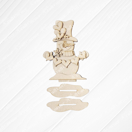 The Hearts Snowman Shelf Sitter DIY craft kit by Janet's Craft Corner includes laser-cut wood pieces to create a festive snowman with a top hat, scarf, and mittens—perfect seasonal home décor or a charming holiday shelf sitter.