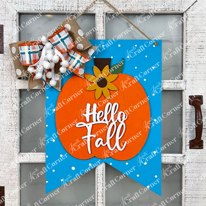 The "Hello Fall Wall Hanger" from Janet's Craft Corner is a handcrafted decoration featuring an orange pumpkin and a sunflower set against a blue background with white dots on a white door. With the text "Hello Fall," it's adorned with a large plaid and pom-pom bow, adding charm to any entrance this autumn.