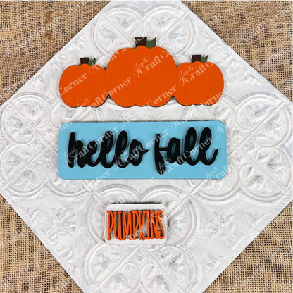 Introducing the **Hello Fall Interchangeable Insert** by *Janet's Craft Corner*: a hand-painted DIY home decor kit. This decorative sign showcases three orange pumpkins along with the phrase "hello fall" artfully scripted in black on a blue background, complemented by "PUMPKINS" elegantly displayed in orange letters. Set on a white textured burlap backdrop, this kit is an ideal addition to your seasonal decor collection.
