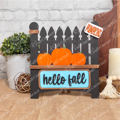 Introducing the "Hello Fall Interchangeable Insert" from Janet's Craft Corner—a charming DIY home decor kit featuring a garden fence carrying orange pumpkins. With "hello fall" inscribed on the blue sign and a "PUMPKINS" sign on the post, it's perfect for seasonal decoration.