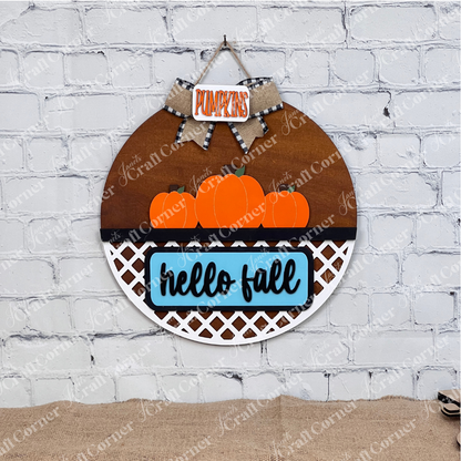 Introducing the "Hello Fall Interchangeable Insert" from Janet's Craft Corner—a charming DIY home decor kit featuring a door hanger carrying orange pumpkins. With "hello fall" inscribed on the blue sign inside the lattice work and a "PUMPKINS" sign on the bow, it's perfect for seasonal decoration.