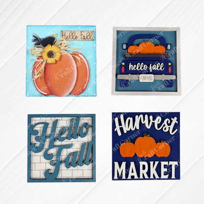 Janet's Craft Corner's Hello Fall Squares set features four charming wood cut-outs: a "Hello Fall" pumpkin, blue truck with pumpkins, brick background, and "Harvest Market" sign—perfect autumn-themed tiered tray decor.