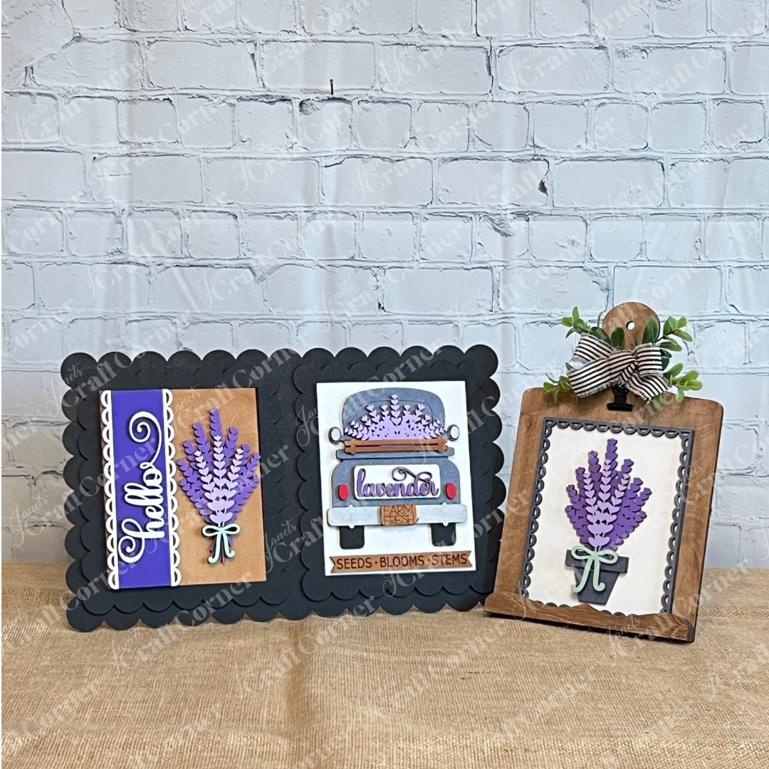 The Lavender Switchable Farmhouse Signs DIY Craft Kit from Janet's Craft Corner features three charming lavender-themed signs—“Hello,” a vintage truck design, and a clipped board with greenery and a striped bow—for your tiered tray décor.
