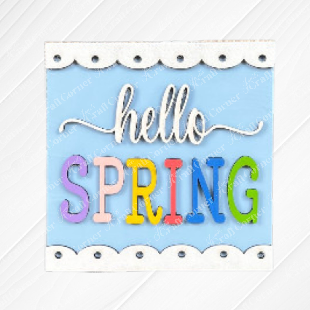 The Hello Spring Squares by Janet's Craft Corner features "hello SPRING" in cursive and bold colors on a blue background—ideal as tiered tray decor or paired with your favorite Swappable Squares wood cut-outs.