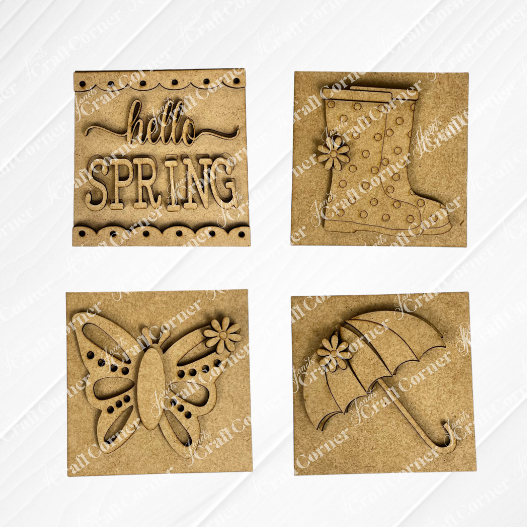 Janet’s Craft Corner Hello Spring Squares include four wood signs: “hello SPRING,” a polka-dot rain boot, a butterfly, and an umbrella—perfect swappable tiered tray decor with charming floral accents.