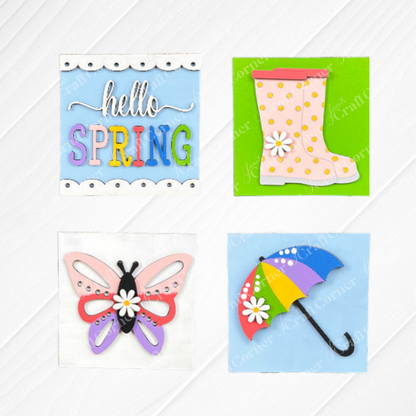Hello Spring Squares by Janet's Craft Corner features four swappable pastel squares: "hello SPRING" with flowers, pink polka dot rain boots, a butterfly, and a rainbow umbrella—perfect for tiered tray decor or wood signs.