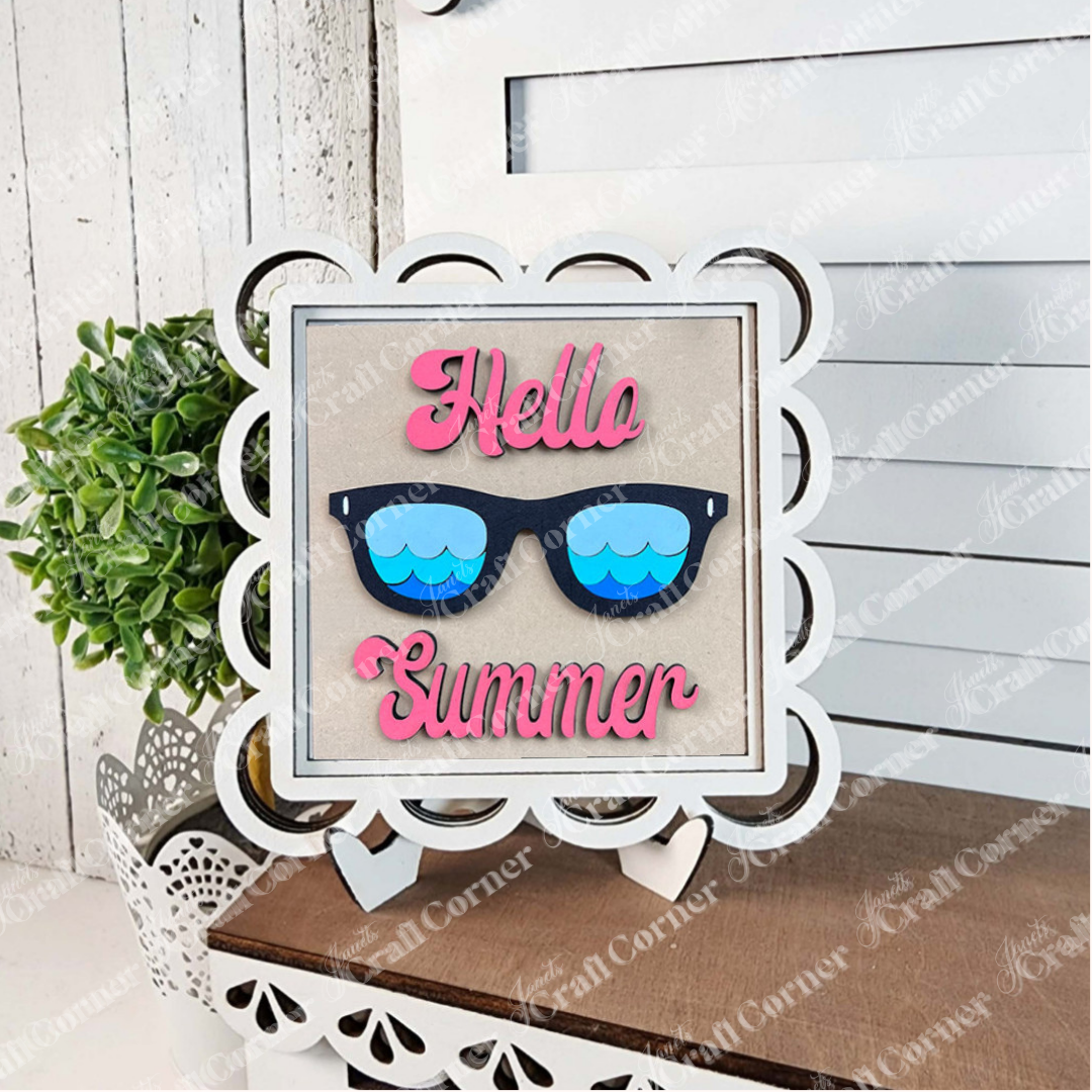 The Summer Lovin Swappable Squares DIY kit by Janet's Craft Corner features a white scalloped sign with pink "Hello Summer" text and black sunglasses, perfect for tiered trays. Part of the Swappable Squares wood cut-outs collection.