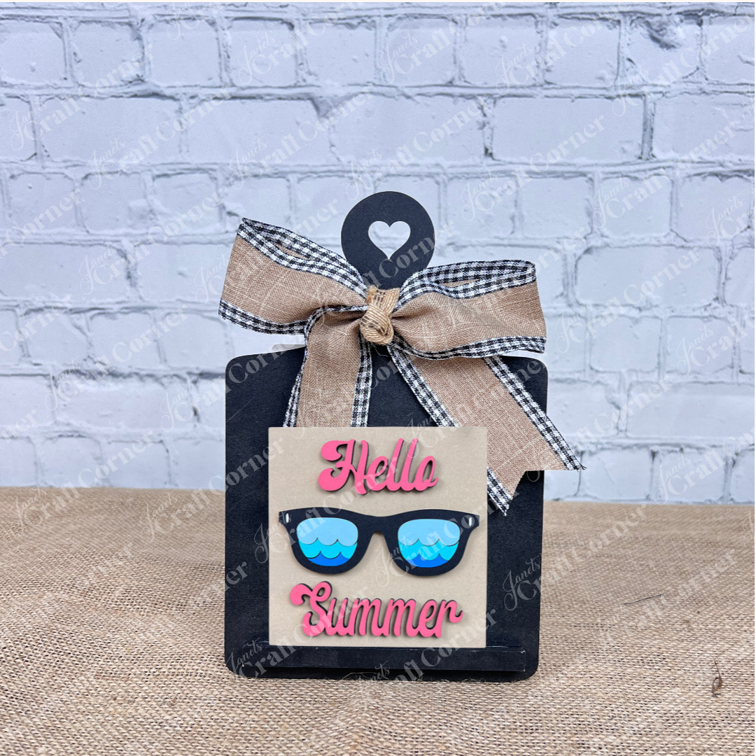 Add a pop of color to your home with the Summer Lovin Swappable Squares DIY craft kit from Janet's Craft Corner—featuring "Hello Summer" in pink, blue sunglasses wood cut-outs, and a burlap plaid bow for eye-catching seasonal decor.